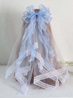 a white and blue wedding veil with ribbon on it's back, sitting on a table