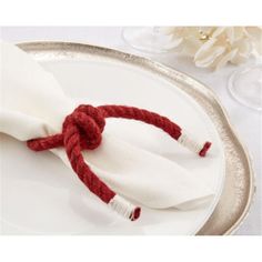 a white plate topped with a red rope on top of a silver rimmed table