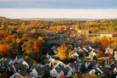 a city with lots of houses and trees in the foreground, surrounded by fall foliage