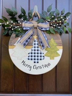 a christmas door hanger decorated with evergreens and plaid ribbon on a wooden door