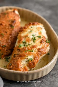 two pieces of chicken parmesan in a dish