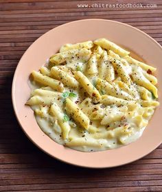 a white plate topped with macaroni and cheese on top of a wooden table