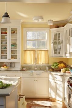 Sunny kitchen with white cabinets, a window above the sink, and a bowl of fruits on the counter. Neutral Kitchen Wall Colors, Vintage Color Combinations, Yellow Kitchen Paint Colors, Bold Kitchen Colors, Kitchen Color Combinations Ideas, Neutral Kitchen Colors Schemes, Yellow Kitchen Paint, Kitchen Color Palette Ideas, Caramel Kitchen