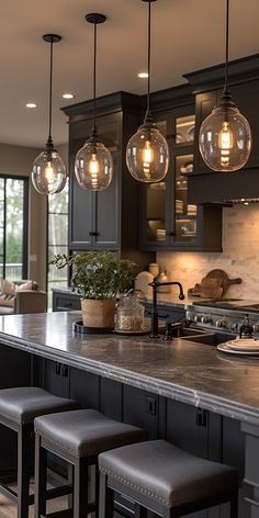 a kitchen island with stools and lights hanging over it