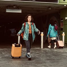 a woman is walking with her luggage at the airport