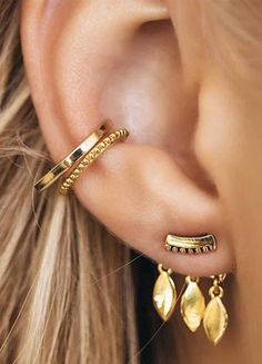 a woman's ear with two gold leaves attached to the side of her ear