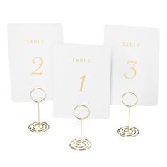 three place cards with gold numbers and circles on each one, sitting next to each other