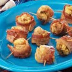 some food is on a blue plate with toothpicks in it and bacon wrapped around them