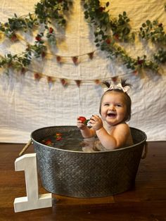 a baby sitting in a metal tub with the number 1 on it's side