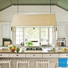 a large kitchen with white cabinets and counter tops, along with two bar stools