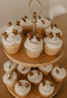 cupcakes are arranged on a three tiered tray with white frosting and brown teddy bears