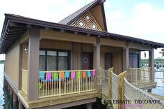 a small house sitting on top of a pier next to the water with colorful sticky notes pinned to it's walls