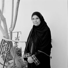 a woman wearing a black hijab standing next to a tree