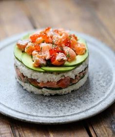 a plate topped with sushi and cucumber on top of a wooden table