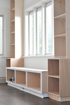 an empty room with wooden shelves and windows