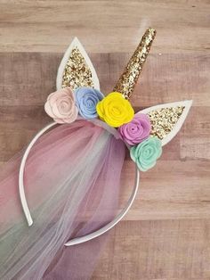 a unicorn headband with flowers and sequins on the top, sitting on a wooden surface