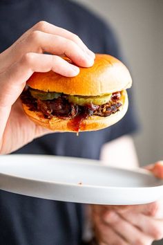 a person holding a plate with a sandwich on it