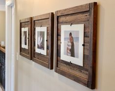 three framed pictures hang on the wall in a hallway with white walls and wood flooring