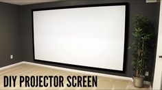 a large screen mounted to the wall in a room with a potted plant next to it