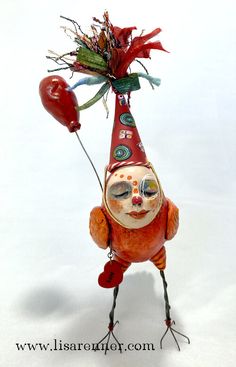 a figurine is holding a balloon and wearing a hat with flowers on it