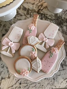 cookies decorated with pink and gold bows on a white platter next to other decorations