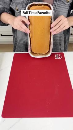 a woman is holding a hot dog in a bun on top of a red mat