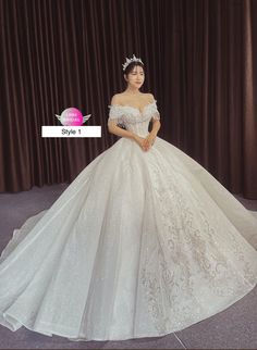 a woman in a white wedding dress standing next to a curtain and wearing a tiara