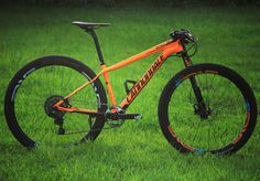 an orange and black mountain bike parked in the grass