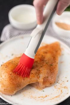 a person using a brush to brush up food on a white plate with sauces