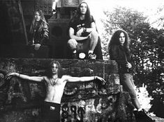 the group of young men are posing in front of a graffiti covered wall with their arms spread out