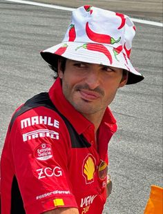 a man wearing a red and white hat sitting on top of a race car track