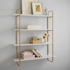 three white shelves with books and vases on them in front of a framed photograph