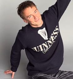 a man sitting on the ground wearing a black sweater