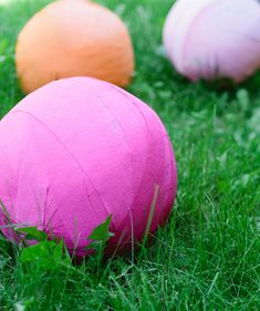 three pink and one orange balls sitting in the grass