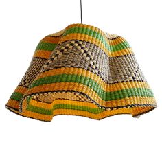 a multicolored lamp shade hanging from a hook on a white wall with a black and green stripe pattern