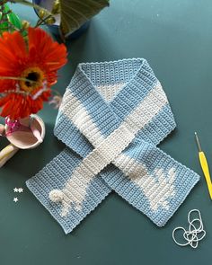 two crocheted coasters sitting on top of a table next to a flower