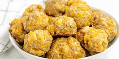 a white bowl filled with meatballs sitting on top of a table next to a napkin