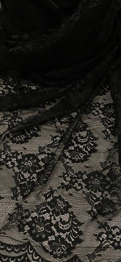 an image of black lace fabric with flowers on it's side, close up