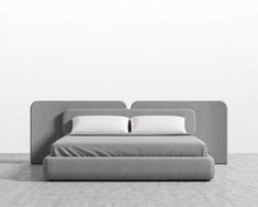 a bed with two pillows on top of it in front of a white wall and floor