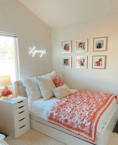 a bedroom with white walls and pictures on the wall above the bed that says happy