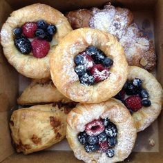 a box filled with pastries covered in berries and powdered sugar on top of each other