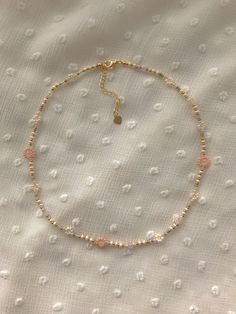 a beaded bracelet with gold beads and a tiny heart charm on the end of it