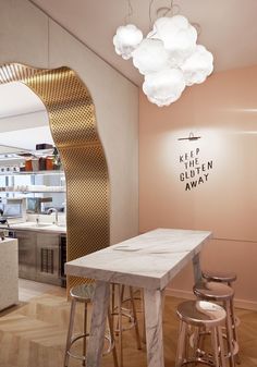 a kitchen with marble counter tops and stools in front of a gold - colored wall