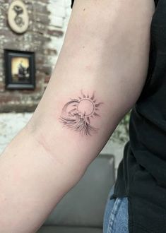 a woman's arm with a small sun and wave tattoo on the left forearm