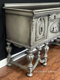 an old dresser is painted silver and has ornate carvings on the top, along with wood floors