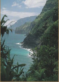 the ocean is blue and green as it sits next to a hill with trees on top