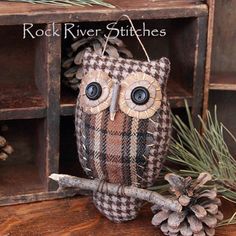 an owl sitting on top of a wooden table next to pine cones and other decorations