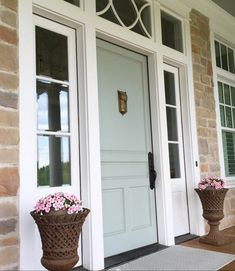 two planters with pink flowers are on the front porch