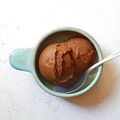 two scoops of chocolate ice cream in a blue bowl on a white counter top