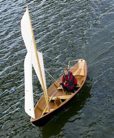 a man is sitting in a small sailboat on the water with no one around